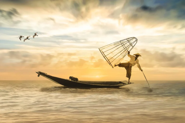 Fisherman balancing on edge of boat