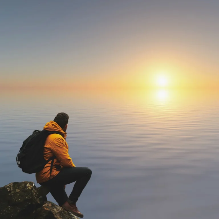 Man looking out at sun over the water