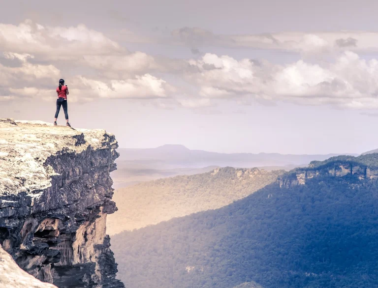 Woman on top of mountain ledge