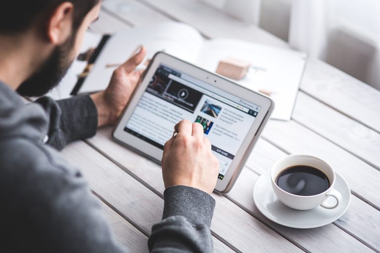 Man using tablet with stylus and coffee cup